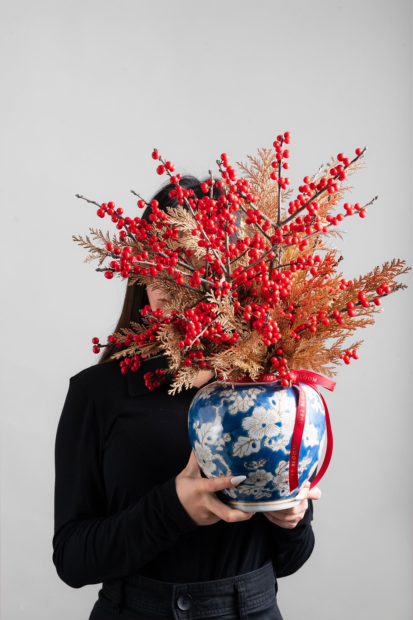 Prosperous Blooms arrangement with red berries, gold foliage, and a blue and white vase, symbolising prosperity and renewal for Lunar New Year.