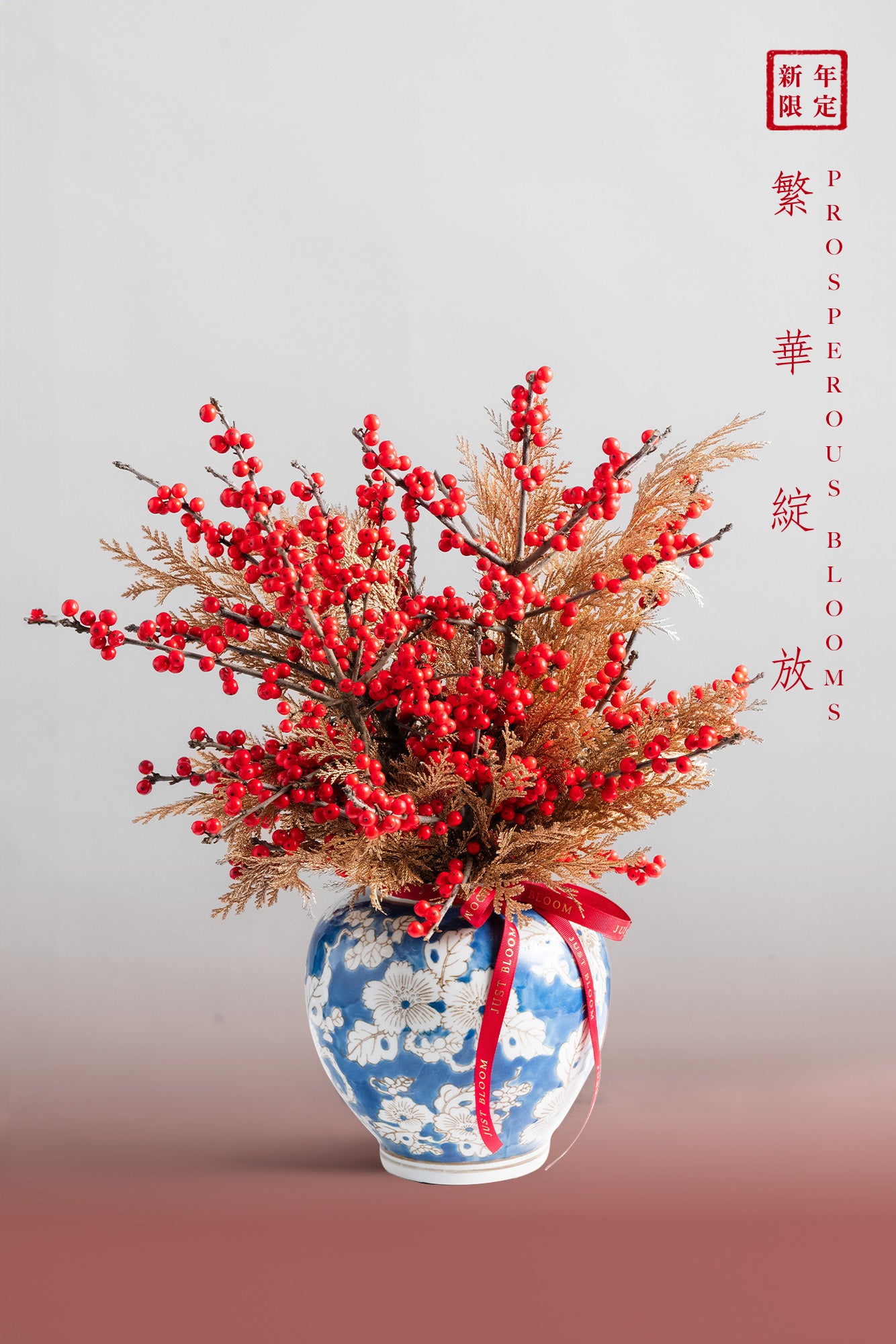 Prosperous Blooms arrangement with red berries, gold foliage, and a blue and white vase, symbolising prosperity and renewal for Lunar New Year.