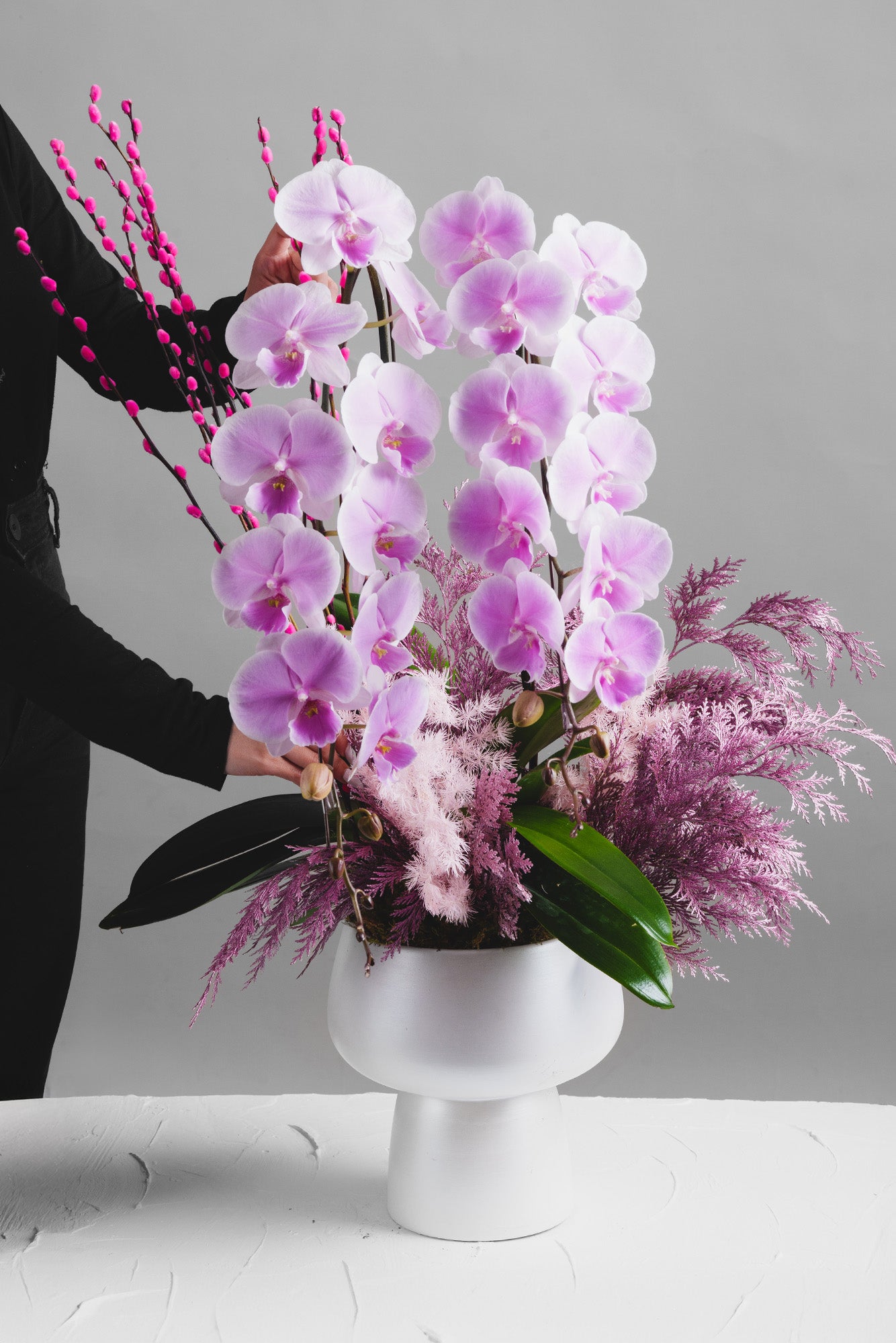 Spring Auspice arrangement with pink orchids, pussy willows, and delicate foliage, symbolising prosperity and harmony for Lunar New Year.