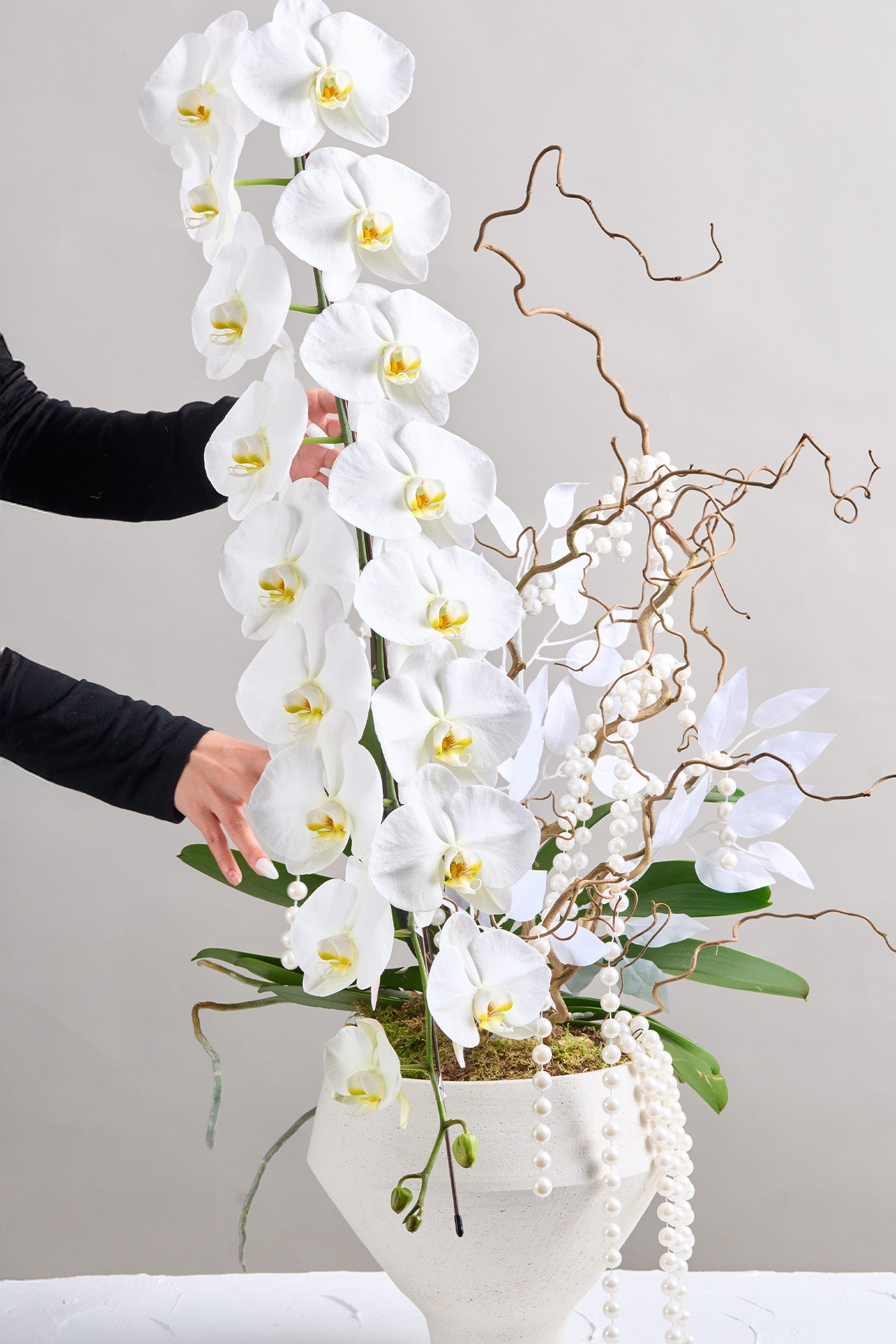 Jade Elegance arrangement with cascading white orchids, intricate branches, and pearl accents, symbolising prosperity and renewal for the Lunar New Year.